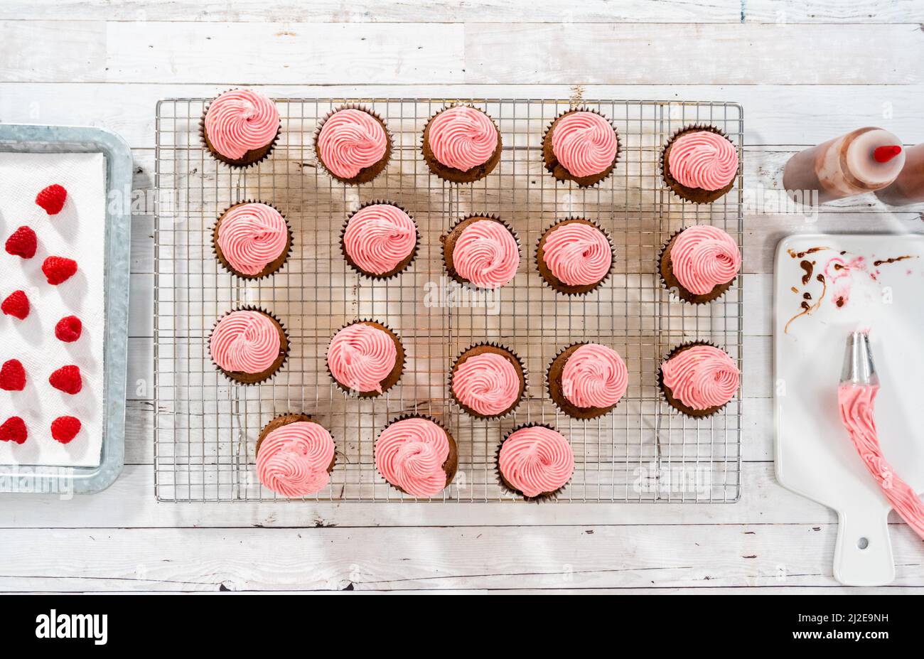 Flat lay. Frosting chocolate cupcakes with raspberry cream cheese