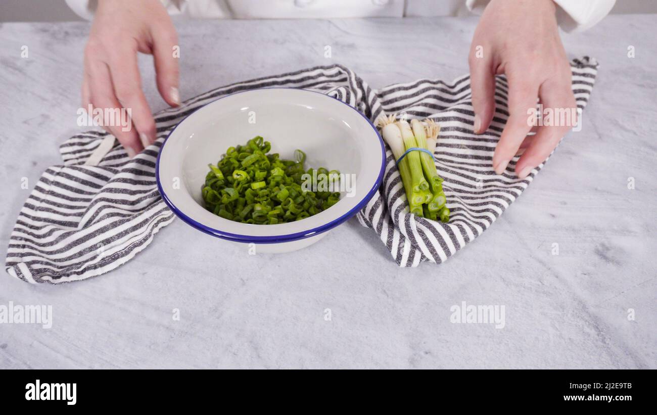 Step by step. Chopping organic green onions on a wood cutting board ...