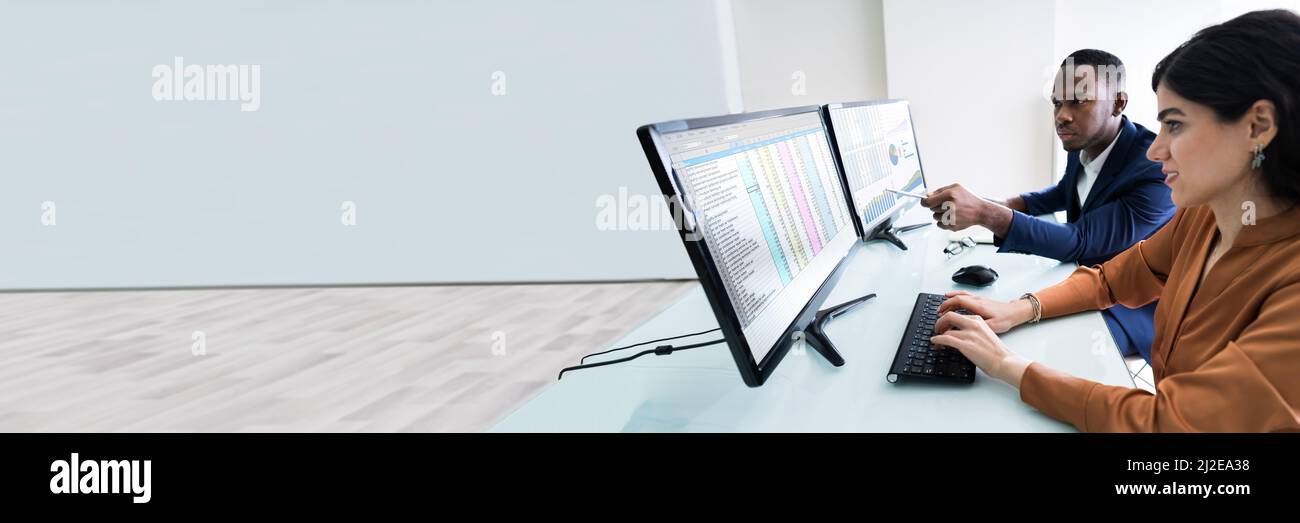 Male And Female Businesspeople Checking Spreadsheet On Computer Screen Over Desk Stock Photo
