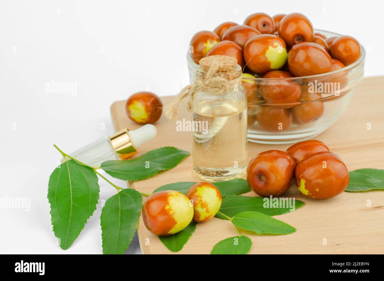 Jojoba oil in a transparent bottle on a wooden table. Fresh fruits and jojoba oil. Stock Photo