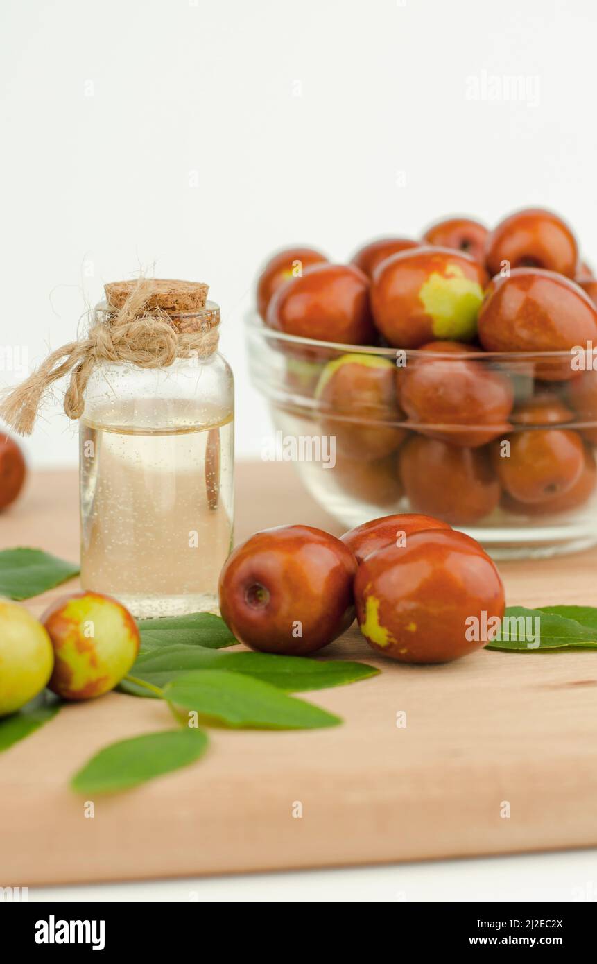Jojoba oil in bottle with cork and fresh jojoba fruit on wooden table Stock Photo