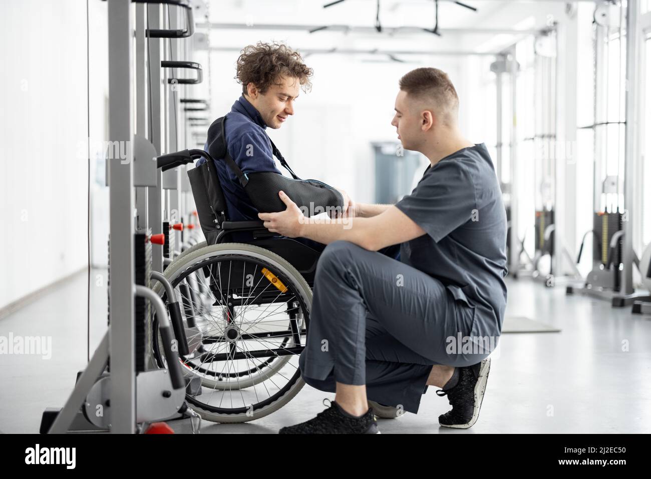 Rehabilitation specialist with guy on a wheelchair doing exercise Stock