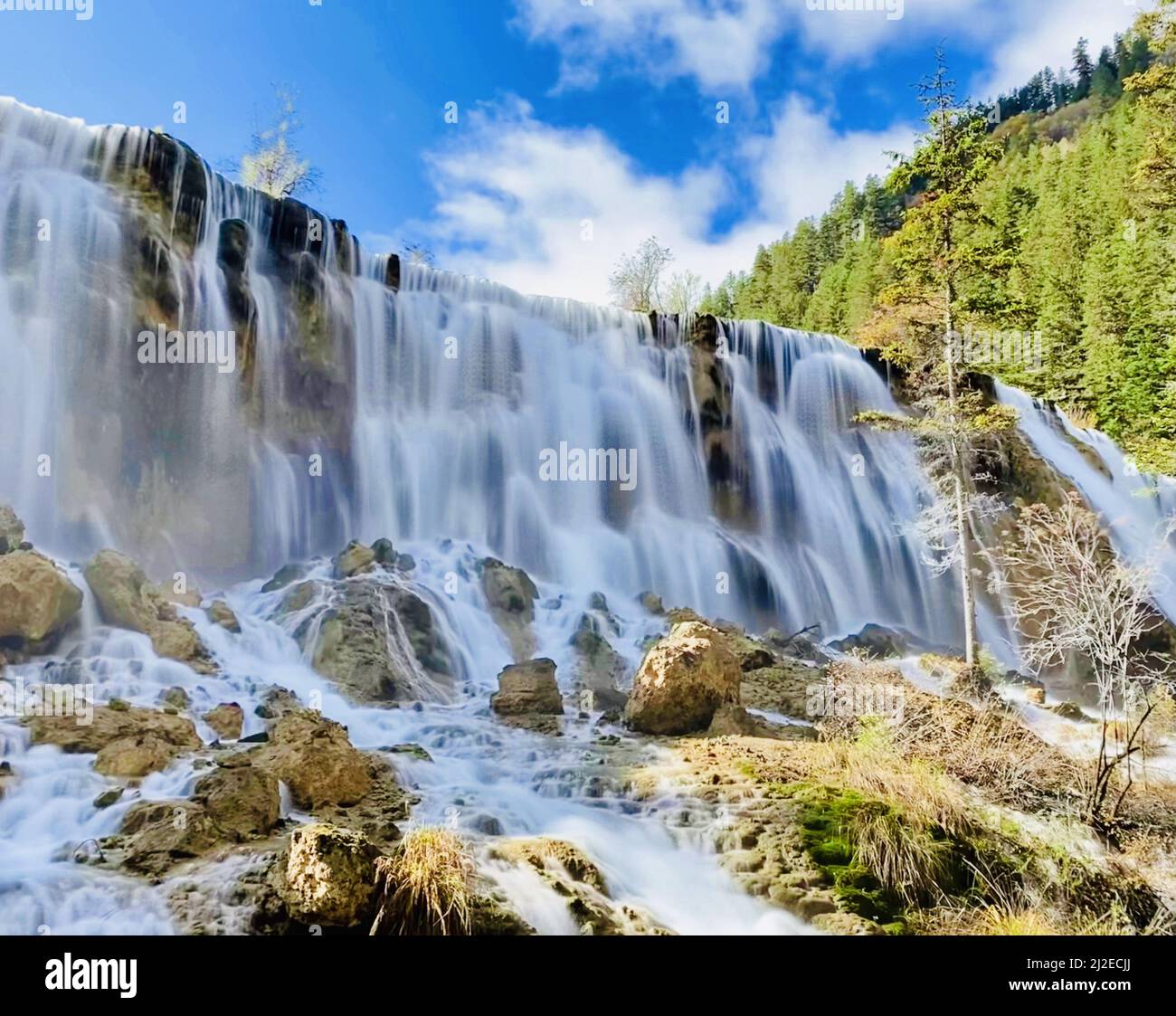 A long exposure of a waterfall flowing down the rocks against green ...