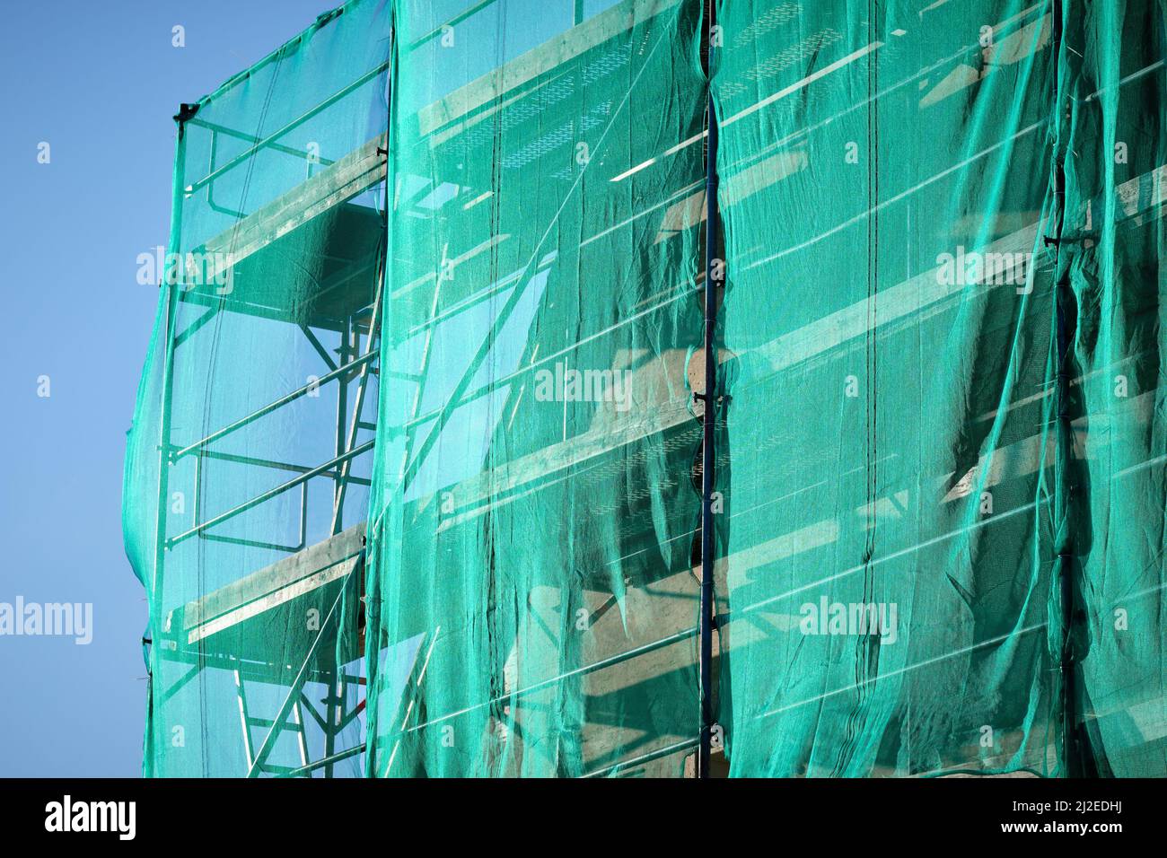 Green safety net in front of a scaffolded facade of a historic building being renovated. Seen in Germany in March. Stock Photo