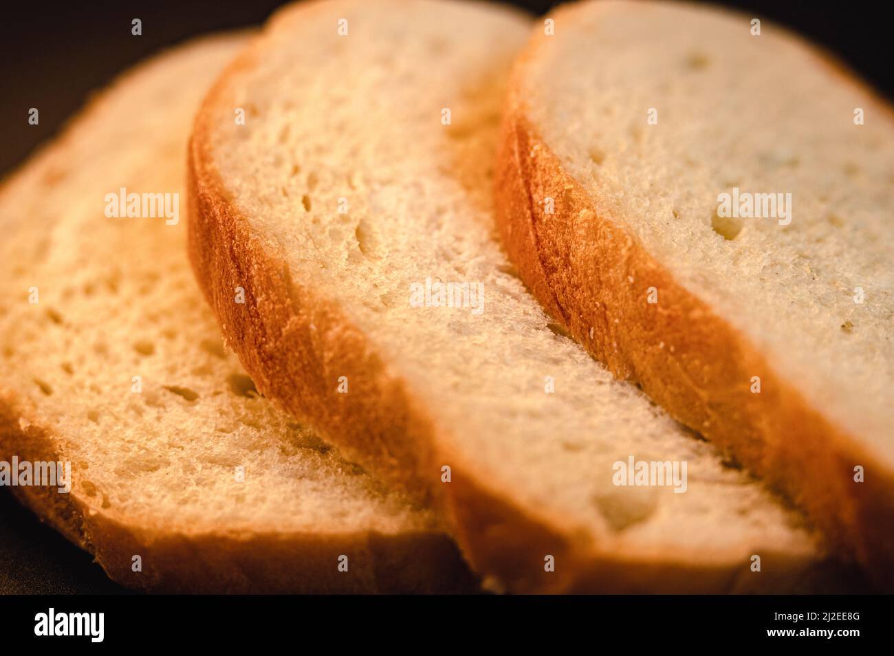 slices of white bread close up on a black background. rough dappled