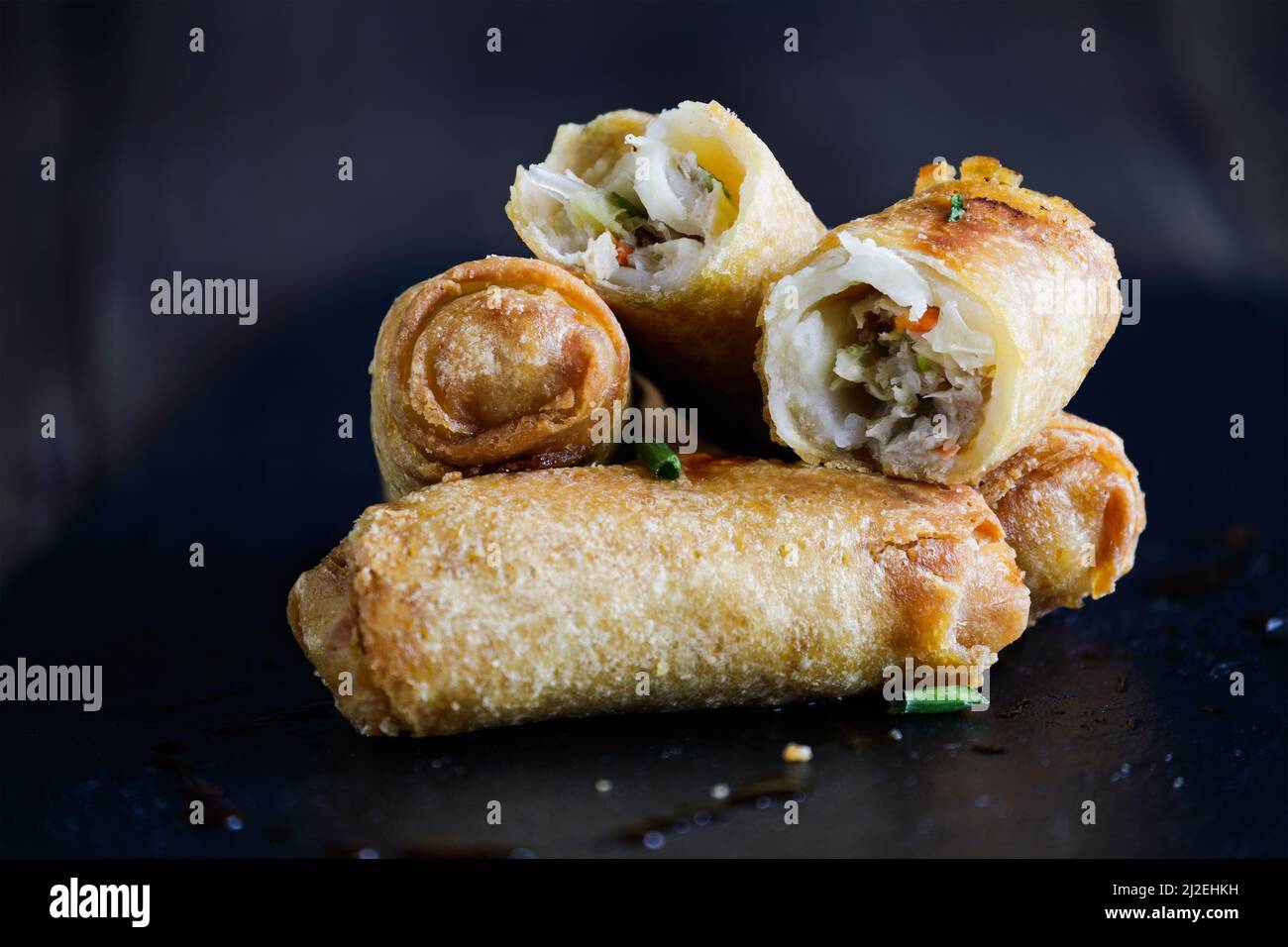 Fresh stack of egg rolls. Top eggroll is broken open to see the ingredients inside.Selective focus with blurred foreground and background. Stock Photo