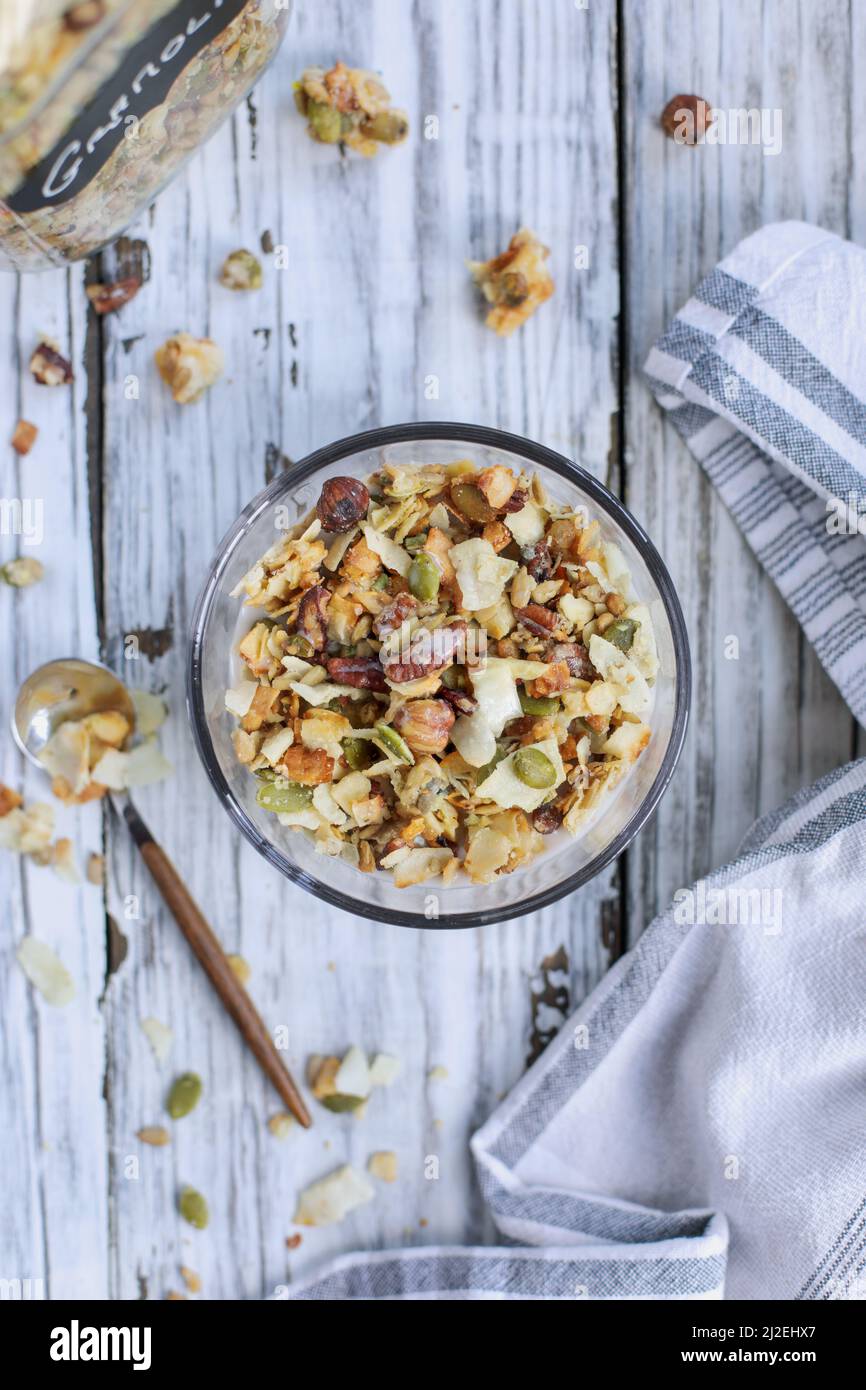 Messy bowl of vegan keto Granola made with pecans, hazelnuts, unsweetened coconut, sunflower seeds, pepita seeds and sweetened with erythritol. Served Stock Photo