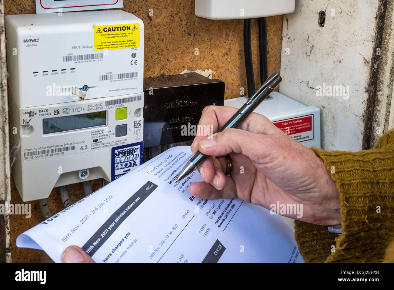 Woman reading or checking electricity meter with an electricity bill. Stock Photo