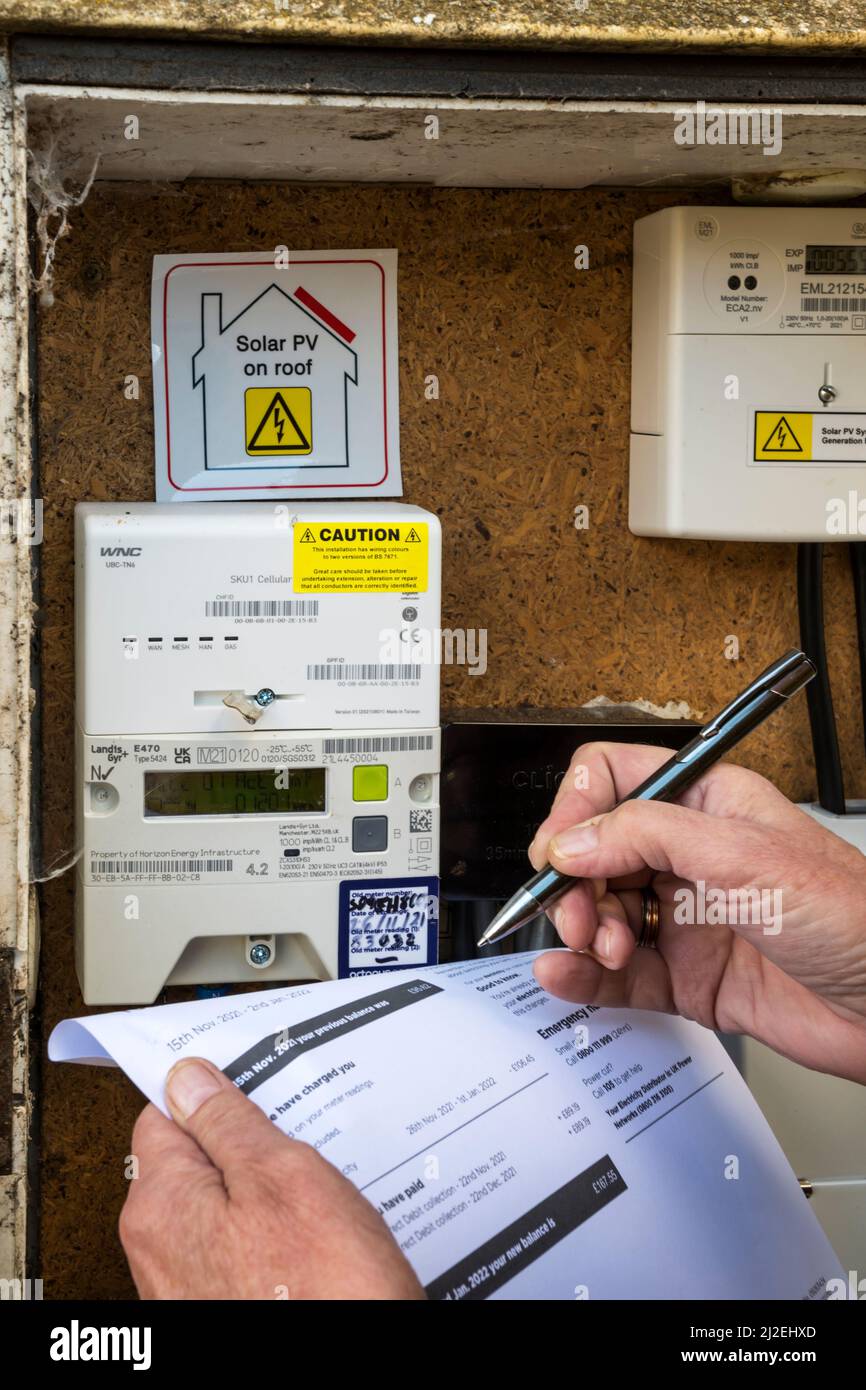 Woman reading or checking electricity meter with an electricity bill. Stock Photo