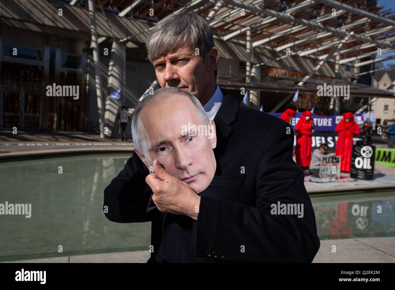 Edinburgh, Scotland, 1 April 2022.  Climate activists from Extinction Rebellion protest outside the Scottish Parliament on day of record energy price rises in UK.  Activists, one wearing a mask of Russian president Vladimir Putin, staged a mock oil spill outside the building to protest the continuing reliance on fossil fuels. Photo credit: Jeremy Sutton-Hibbert/Alamy Live News. Stock Photo