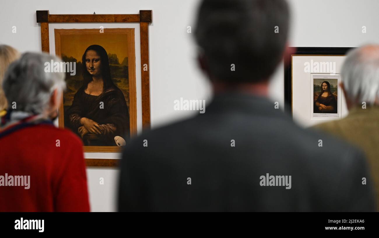 01 April 2022, Hessen, Frankfurt/Main: Participants in a press conference stand in front of reproductions of the Mona Lisa by French artist Marcel Duchamp (1887-1968) at Frankfurt's Museum für Moderne Kunst (MMK). The exhibition 'Marcel Duchamp' will present almost 700 works by the artist from all creative phases from 1902 to 1968 from April 1 to October 3, 2022. Photo: Arne Dedert/dpa Stock Photo