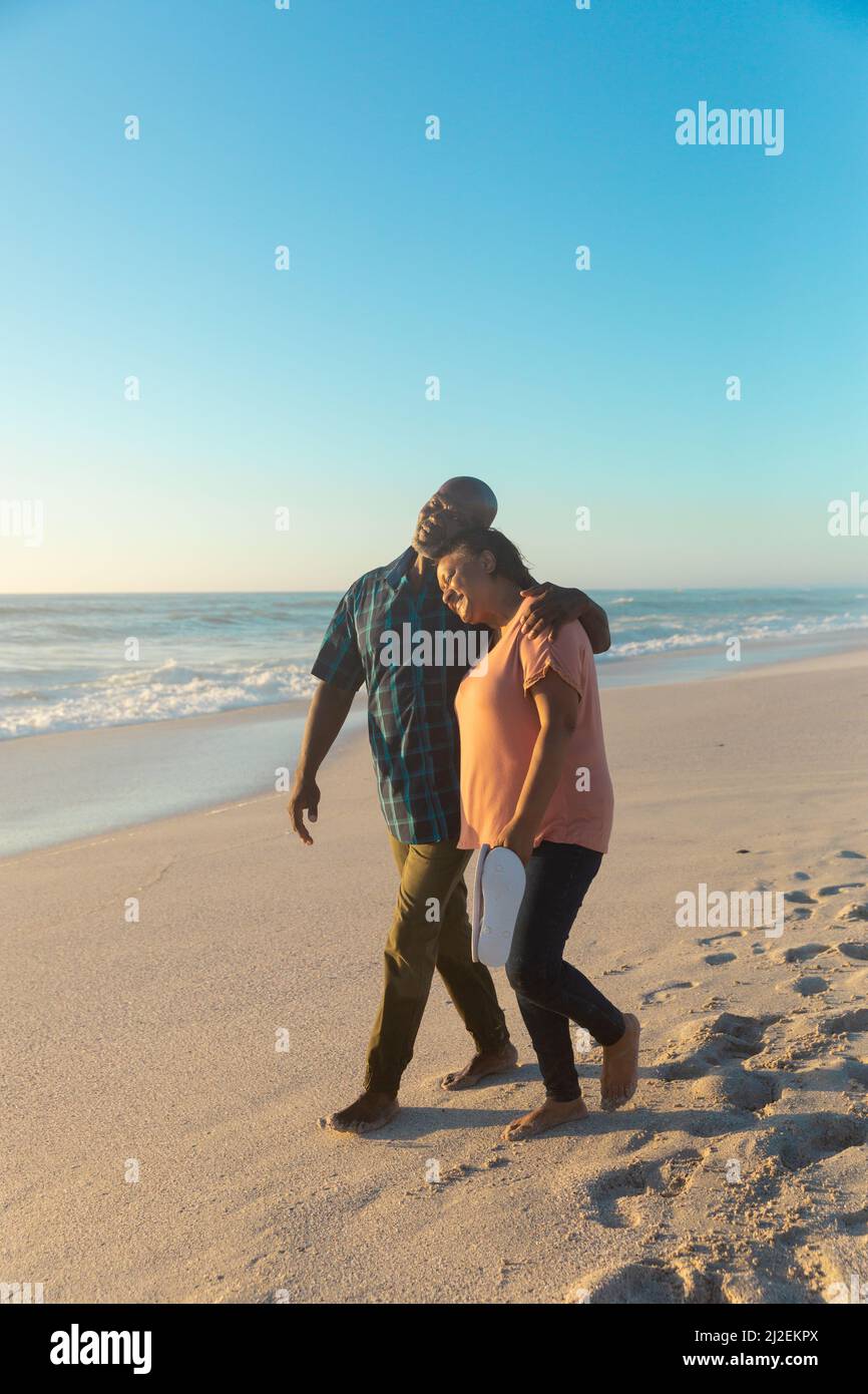African american retired senior couple walking together at beach ...