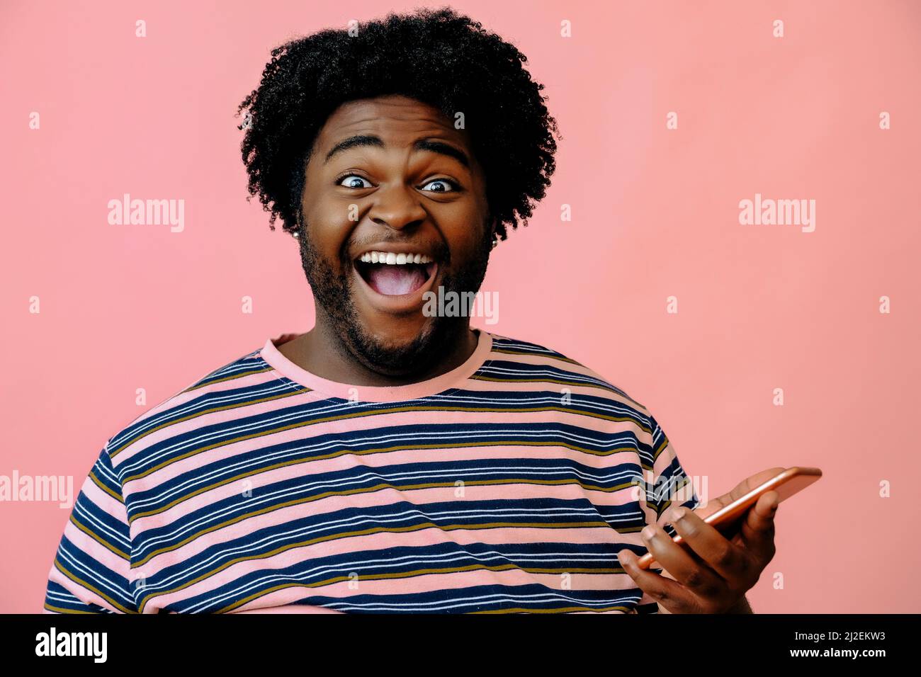 young happy african american man posing in the studio over pink background male model Stock Photo