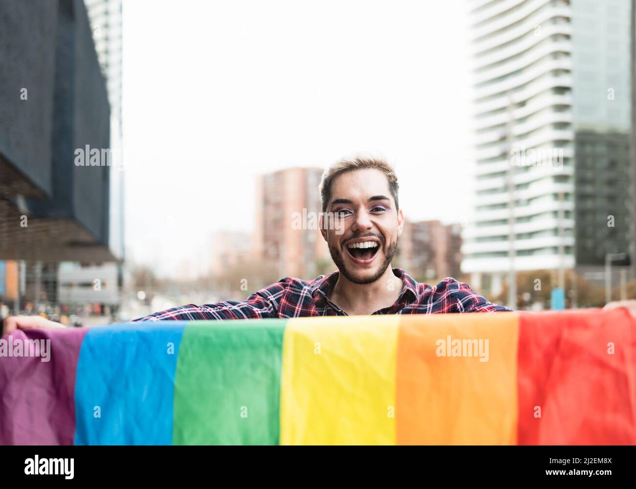 Happy gay man having fun holding rainbow flag symbol of LGBTQ community Stock Photo