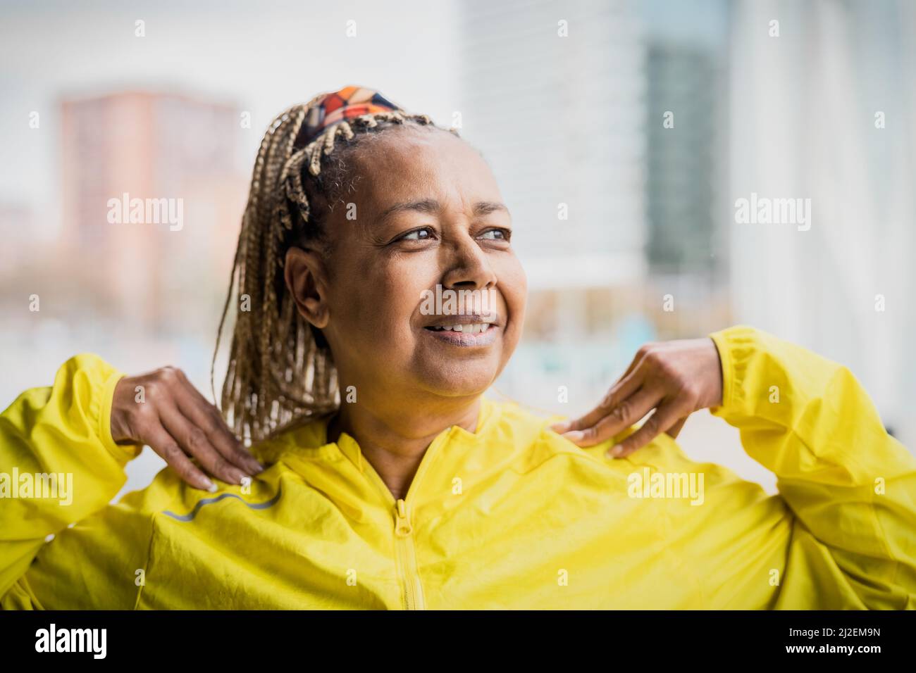 Senior African woman doing warm up exercises before running in the city Elderly Sporty people