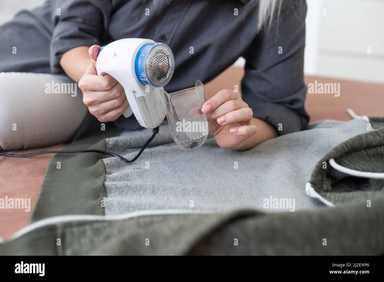 woman uses a machine for removing pellet and spools from clothes and fabric  on black trousers. A modern electronic device for updating old things Stock  Photo - Alamy