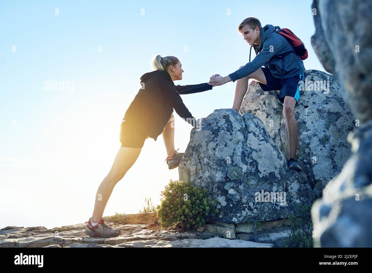 Lemme give you a hand. Full length shot of a young man helping his girlfriend while hiking. Stock Photo