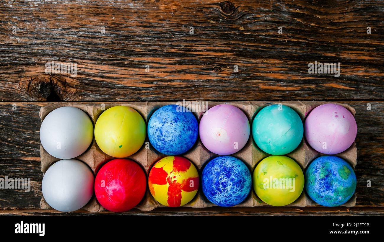 Painted and colored Easter eggs on rustic wooden table inside paper container with copy space above Stock Photo