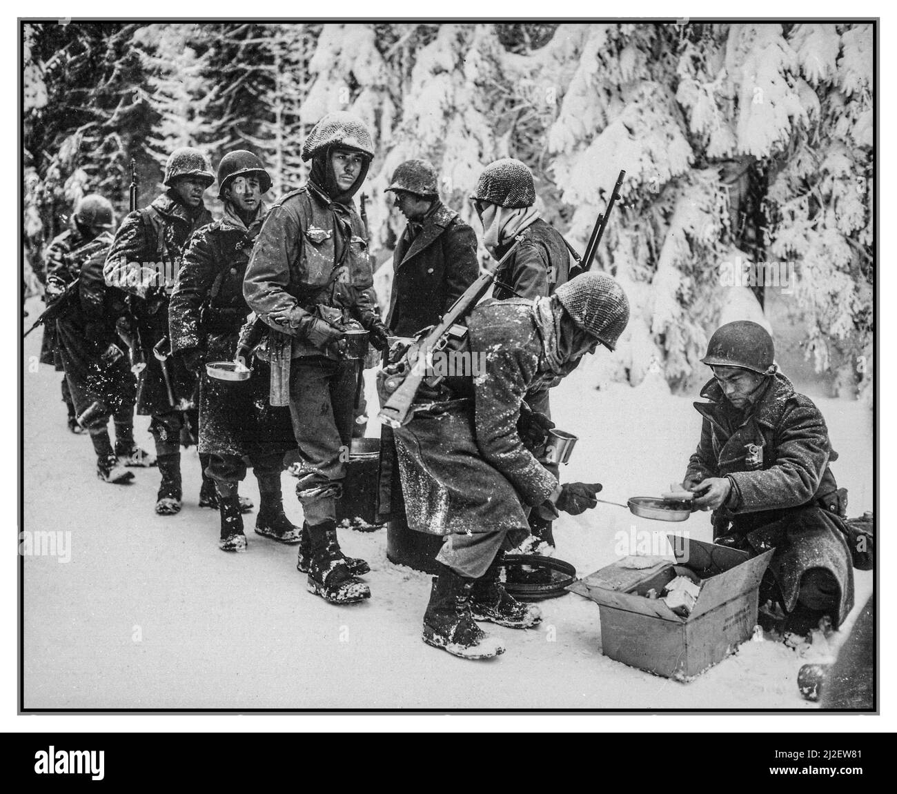 WW2 BATTLE OF THE BULGE ARDENNE ARDENNES Infantry Hot Winter Food Rations are served to American Infantrymen in freezing conditions on the move during their Forest of Ardenne advance to La Roche, Belgium. 347th US Infantry Regiment Winter snow conditions 13 January 1945 World War II Second World War Stock Photo