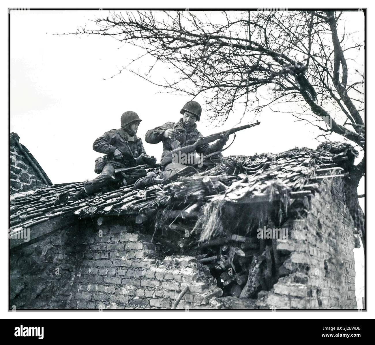 BATTLE OF THE BULGE  S/Sgt. Urban Minicozzi and Pfc. Andy Masiero stop to reload while sniping snipers form the roof of a building in Beffe, Belgium. 1st Battalion, 290th Infantry Regiment, 75th Infantry Division.'  Photographer: Corrado Date 7 January 1945 World War II Second World War Stock Photo