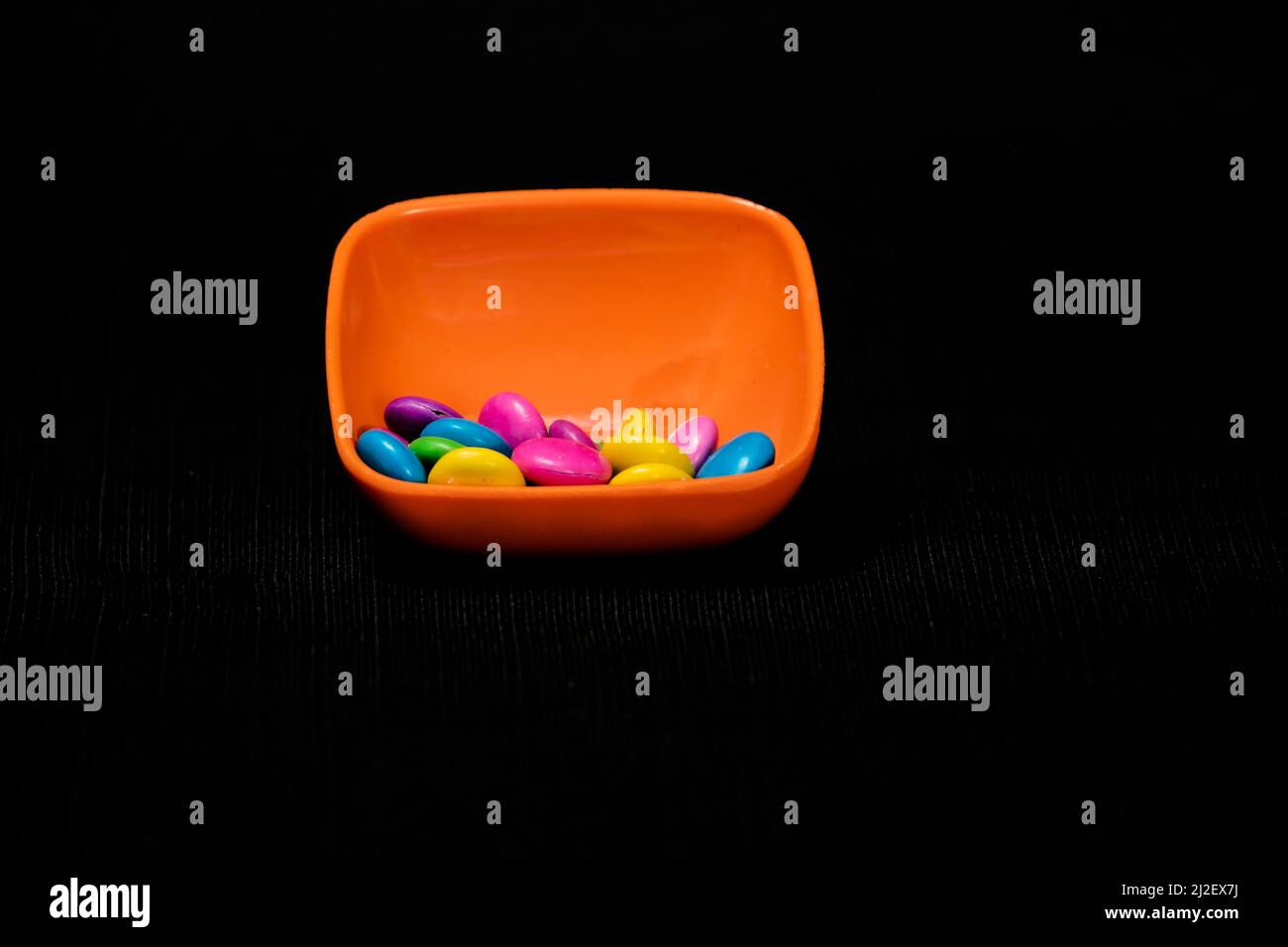 Multi Color Gems Chocolate in Saffron Color Small Square Bowl Isolated