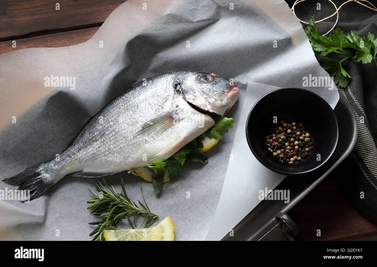 Cooking concept. Delicious fresh fish with aromatic herbs, spices and lemon ready to cook. Sea bream. Healthy food, diet. Directly above. Stock Photo