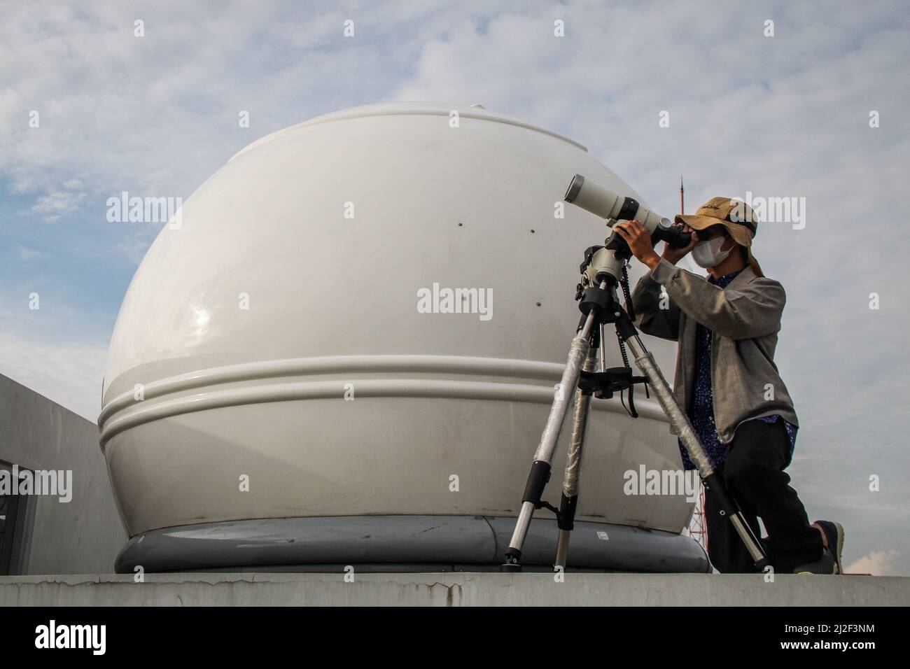 An Indonesian Muslim uses binoculars to see the new crescent moon and
