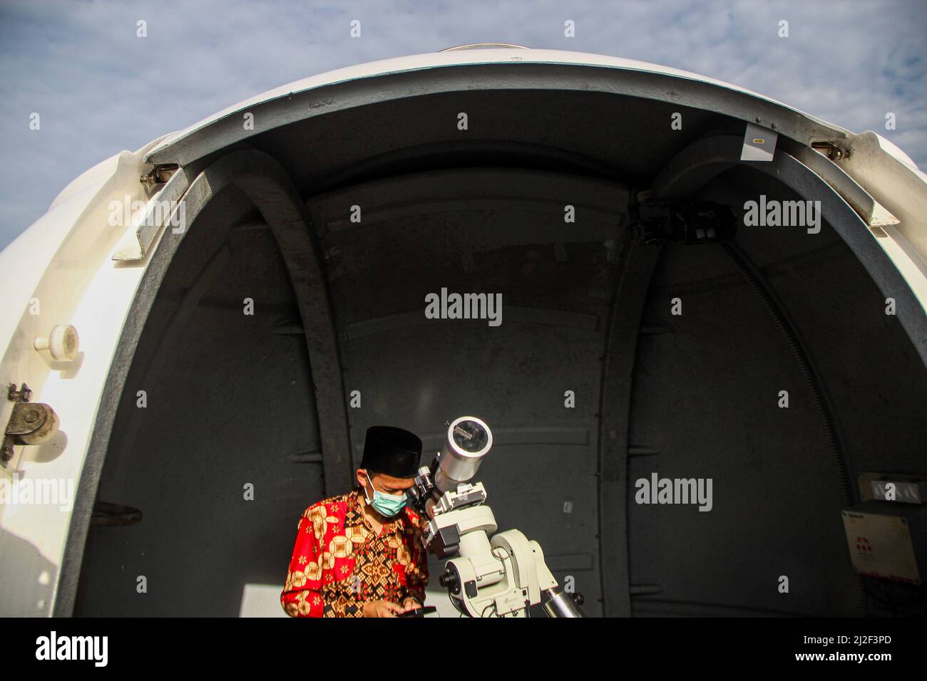 An Indonesian Muslim uses binoculars to see the new crescent moon and