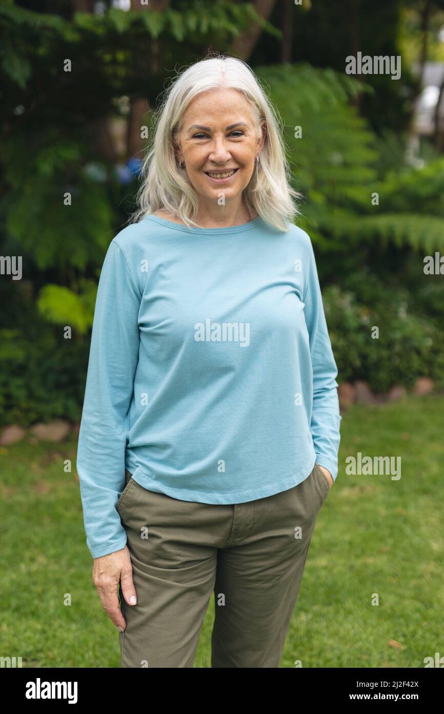 Portrait of happy caucasian senior woman with white hair standing in backyard Stock Photo