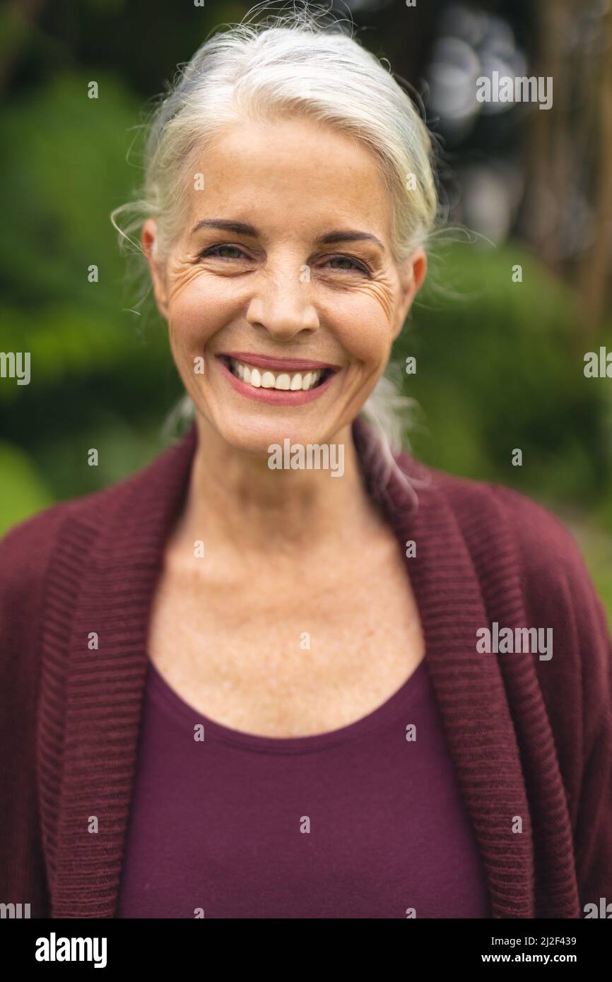 Portrait of cheerful caucasian senior woman with white hair standing in backyard Stock Photo