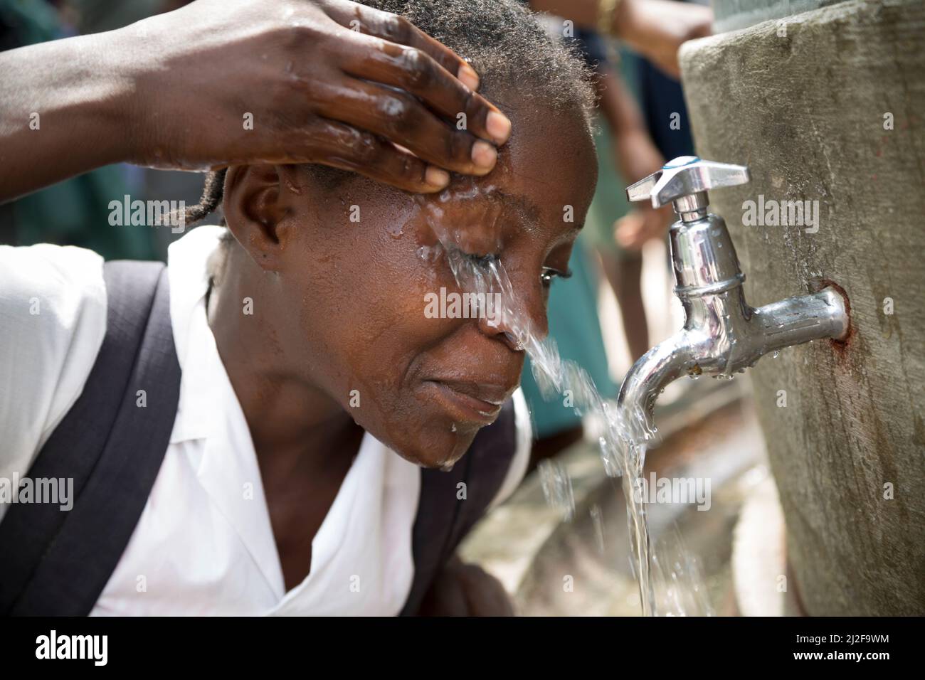 School students access clean drinking and washing water from a fountain in their school courtyard in Oshana Region, Namibia, Africa. Stock Photo