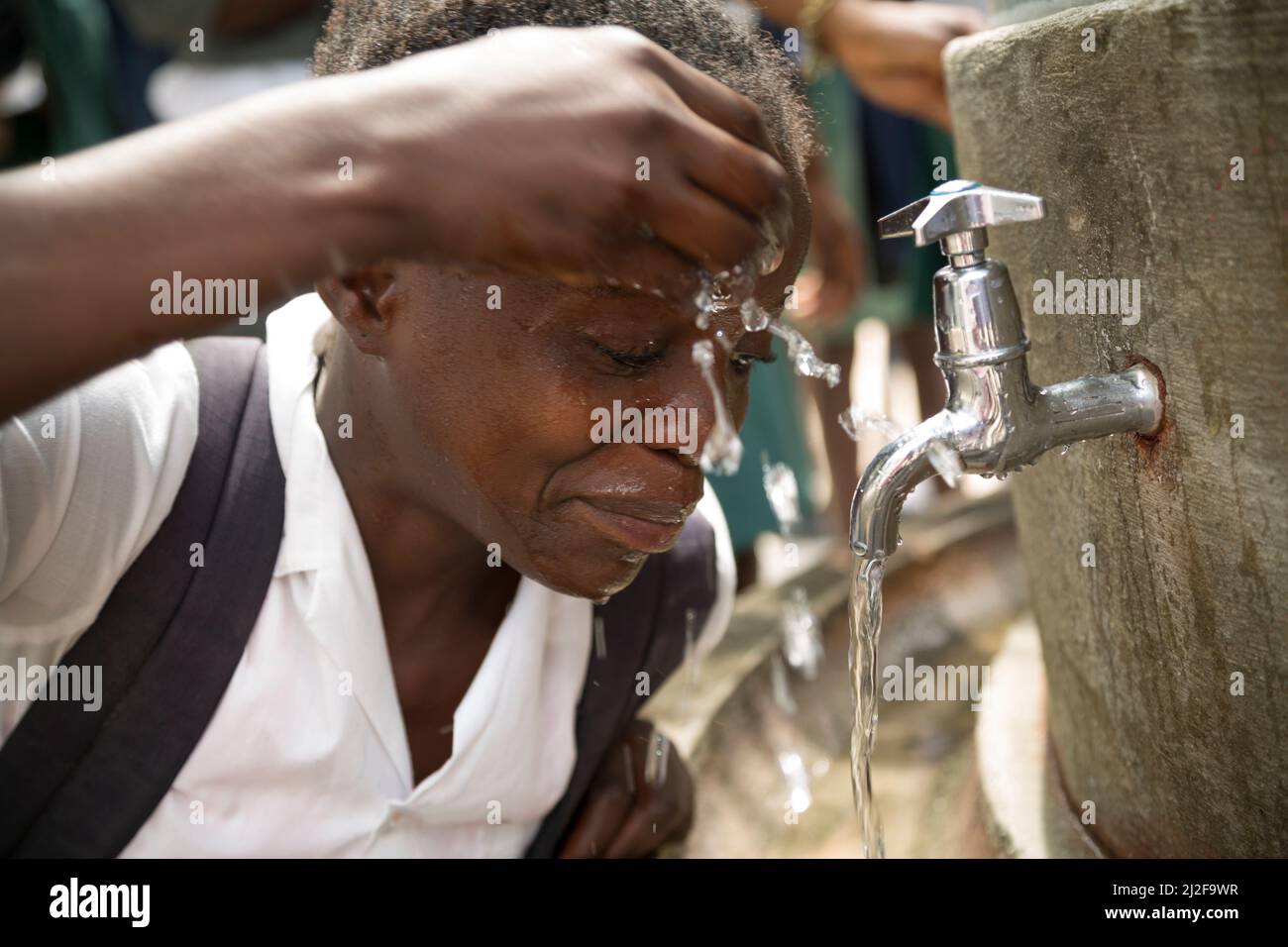 School students access clean drinking and washing water from a fountain in their school courtyard in Oshana Region, Namibia, Africa. Stock Photo