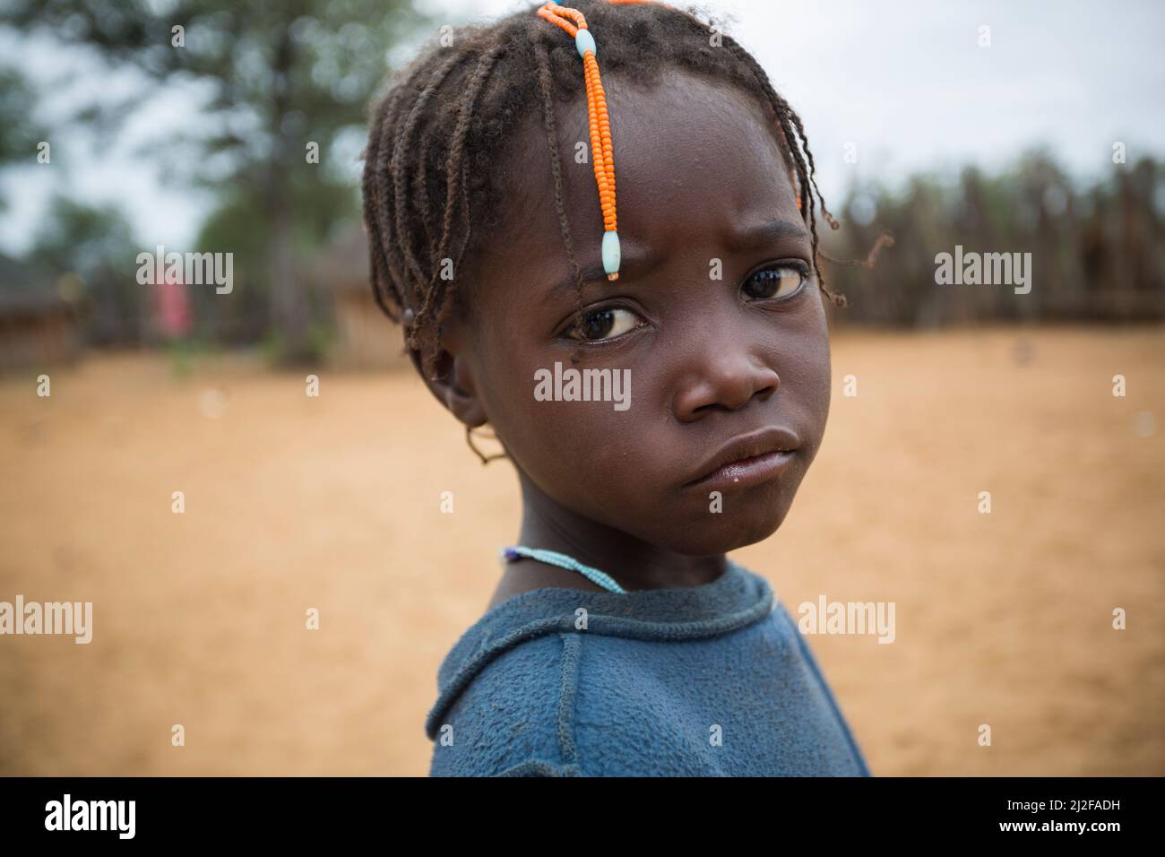 Girl with traditional hair braids and a sad expression in Omusati Region, Namibia, southwest Africa. Stock Photo
