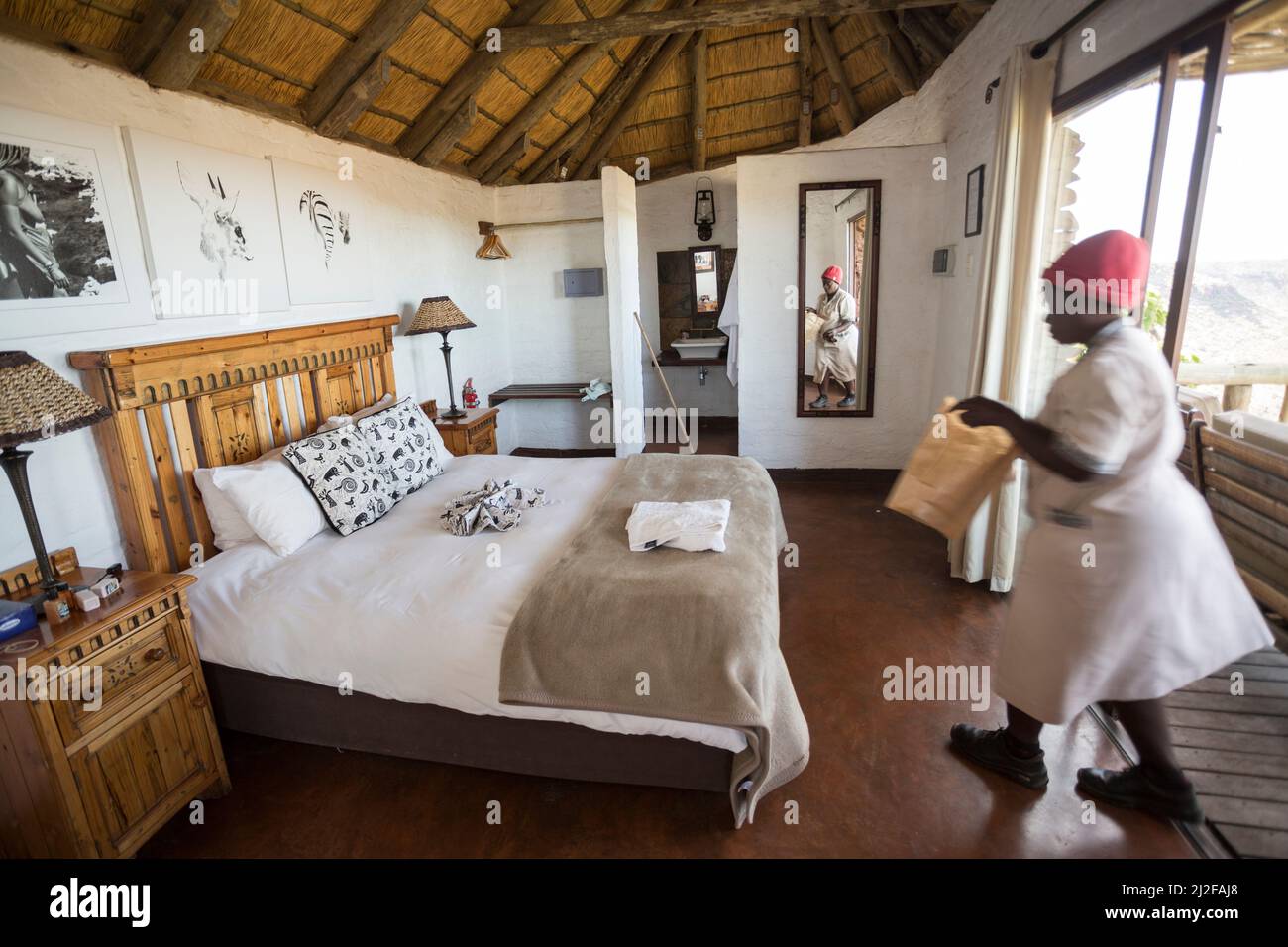 A maid makes up a bed in Grootberg Lodge, a high-end tourist lodge in Kunene Region, Namibia, southwest Africa. Stock Photo