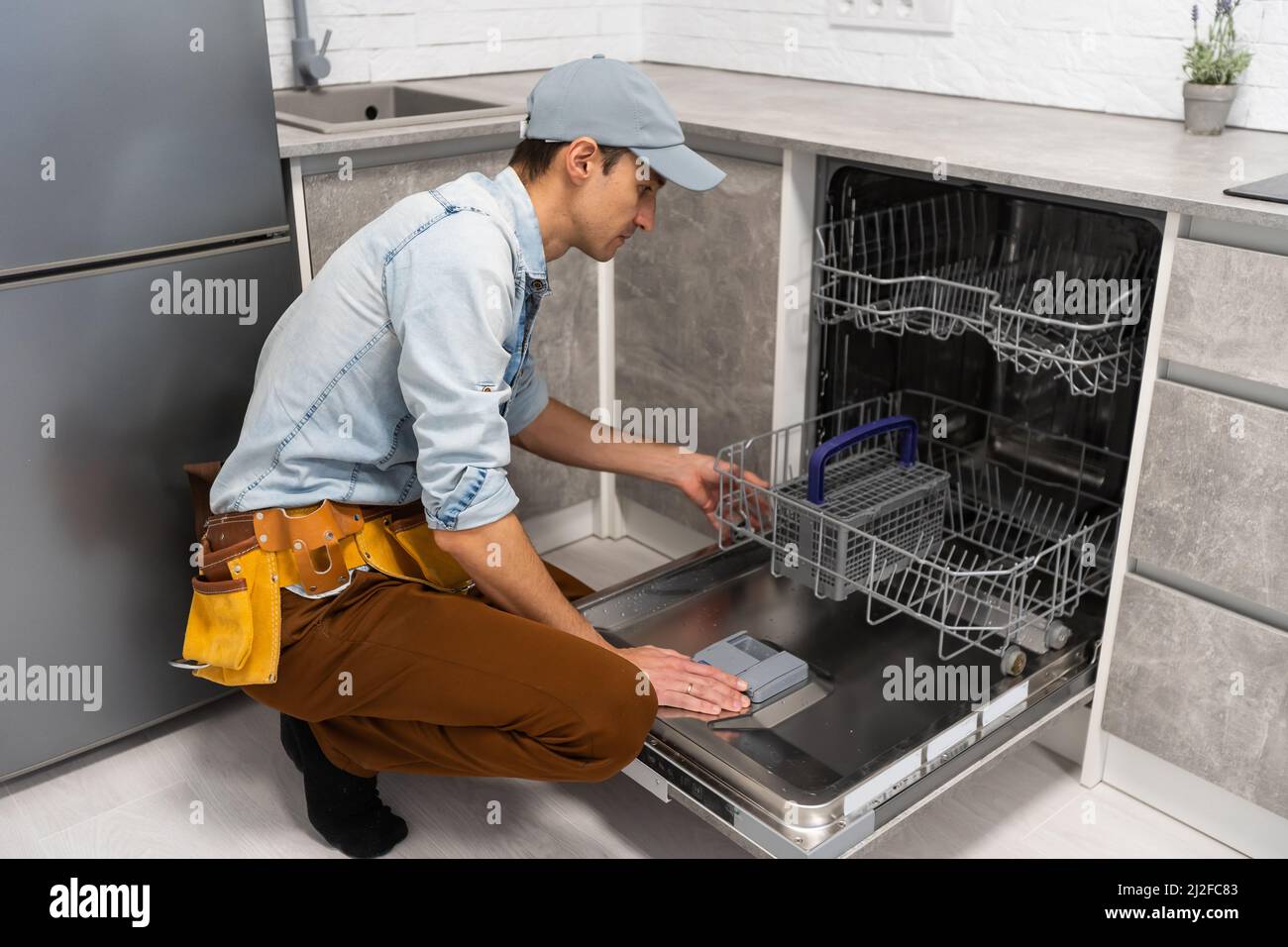 Process of dishwashing machine installation. Young service man setting