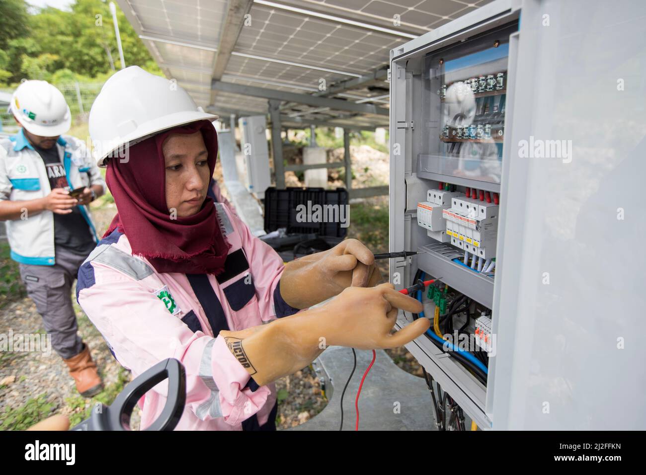 Junior electrical technician, Verawati (23), inspects and maintains solar panels on Karampuang Island, Indonesia, which were installed as part of the Stock Photo