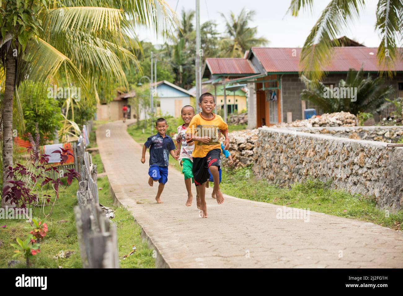 Children race down a village road on Karampuang Island, Indonesia, Asia. Stock Photo