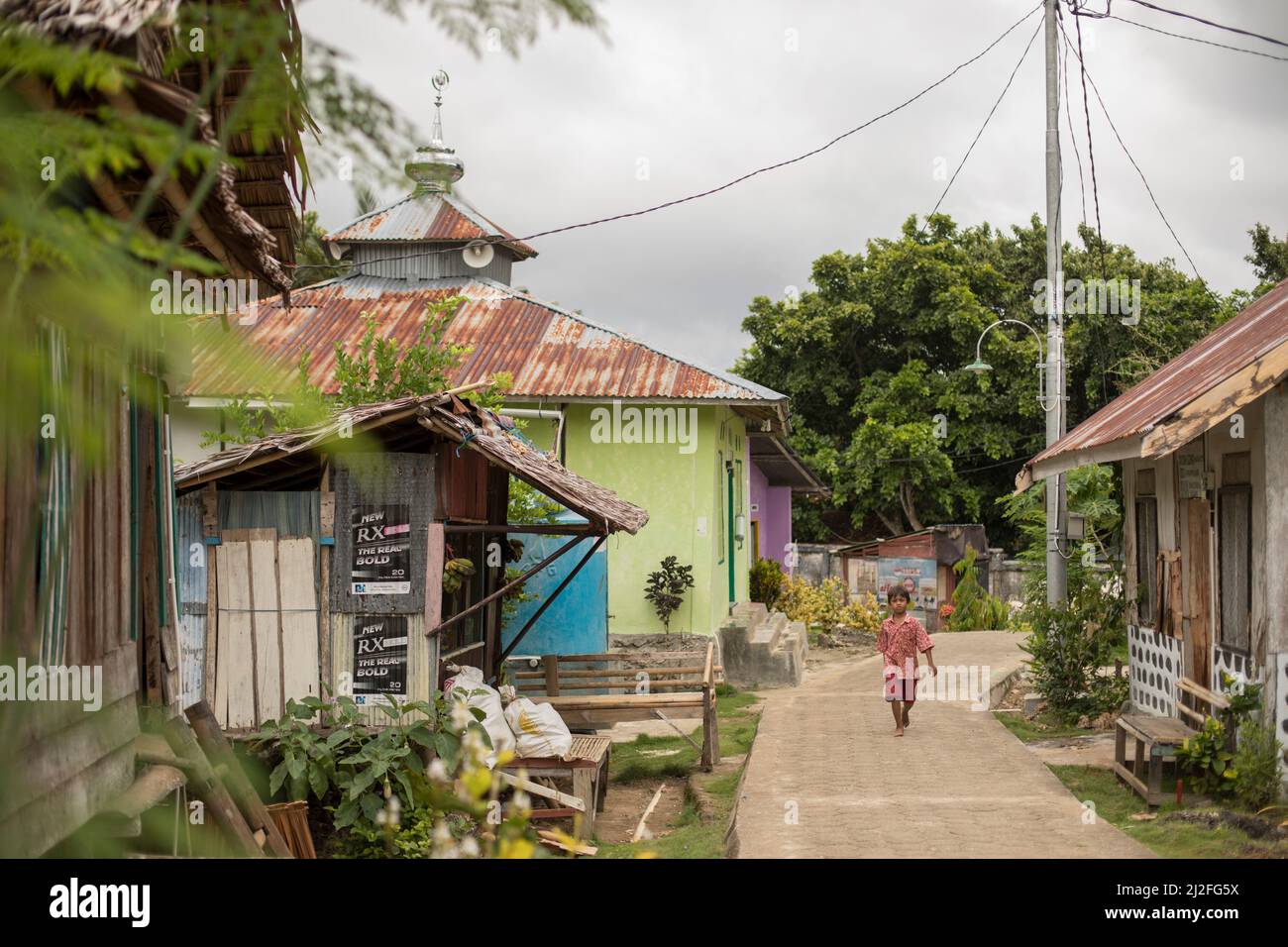 Pedestrian walking down a village lane on the remote Indonesian Island of Karampuang, off the coast of Mamuju, Sulawesi. Stock Photo