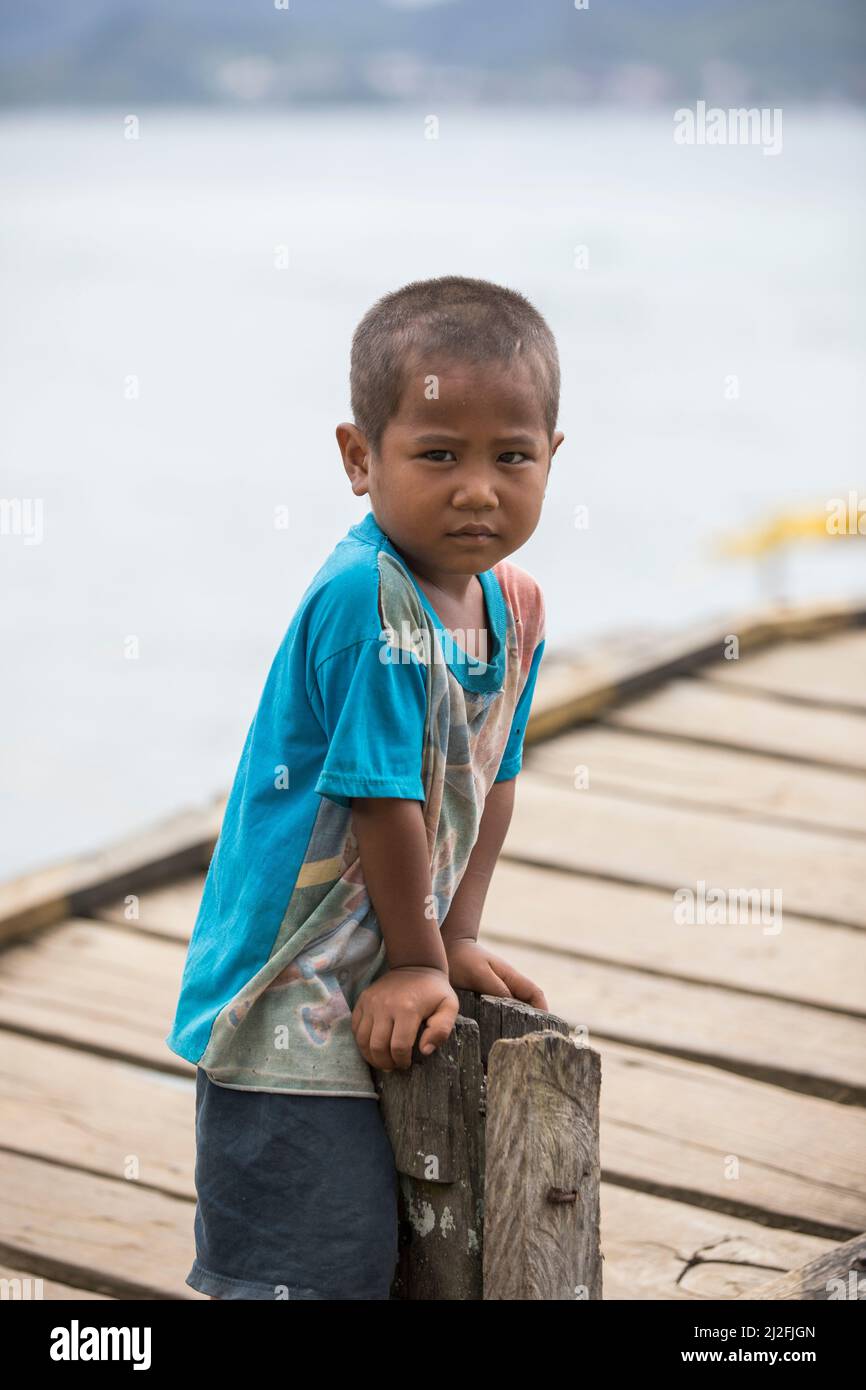 Young boy child with sad expression on a fishing pier on the island of Karampuang, Indonesia, Asia. Stock Photo