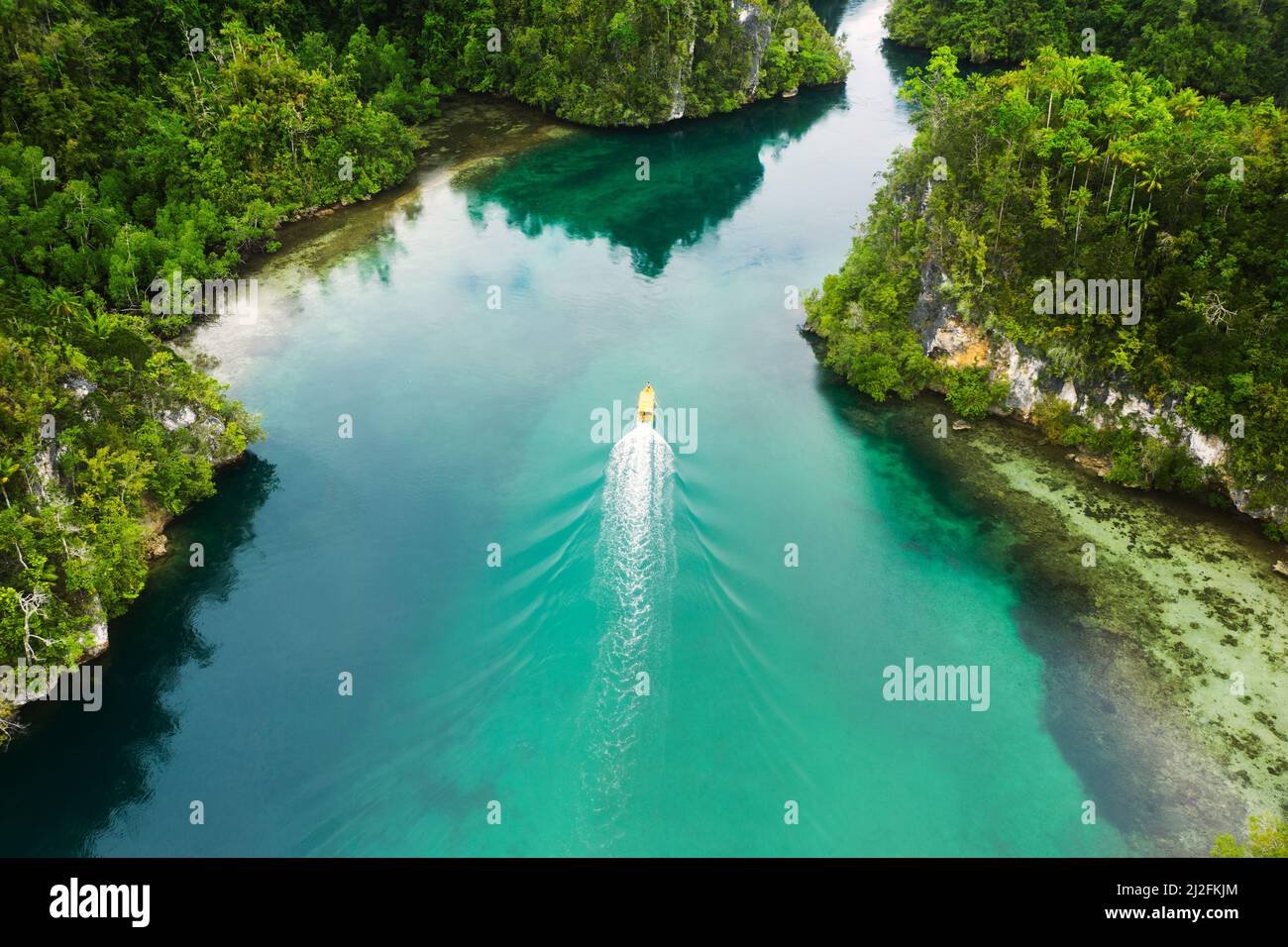 Theres so much beauty found out here. High angle shot of a boat sailing through a canal running along the Raja Ampat Islands in Indonesia. Stock Photo