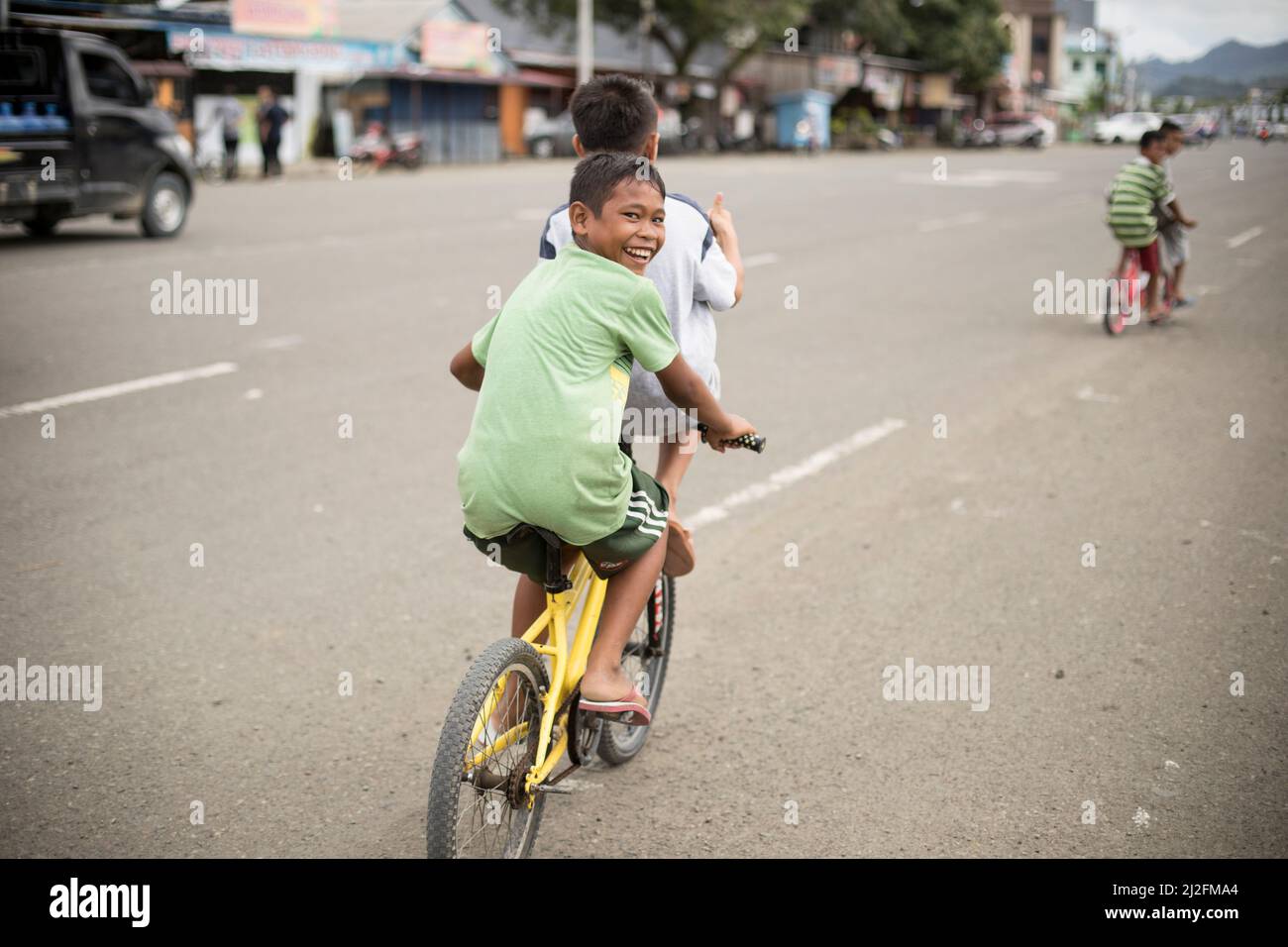 Children ride bikes in the streets of Mamuju, Indonesia. Stock Photo