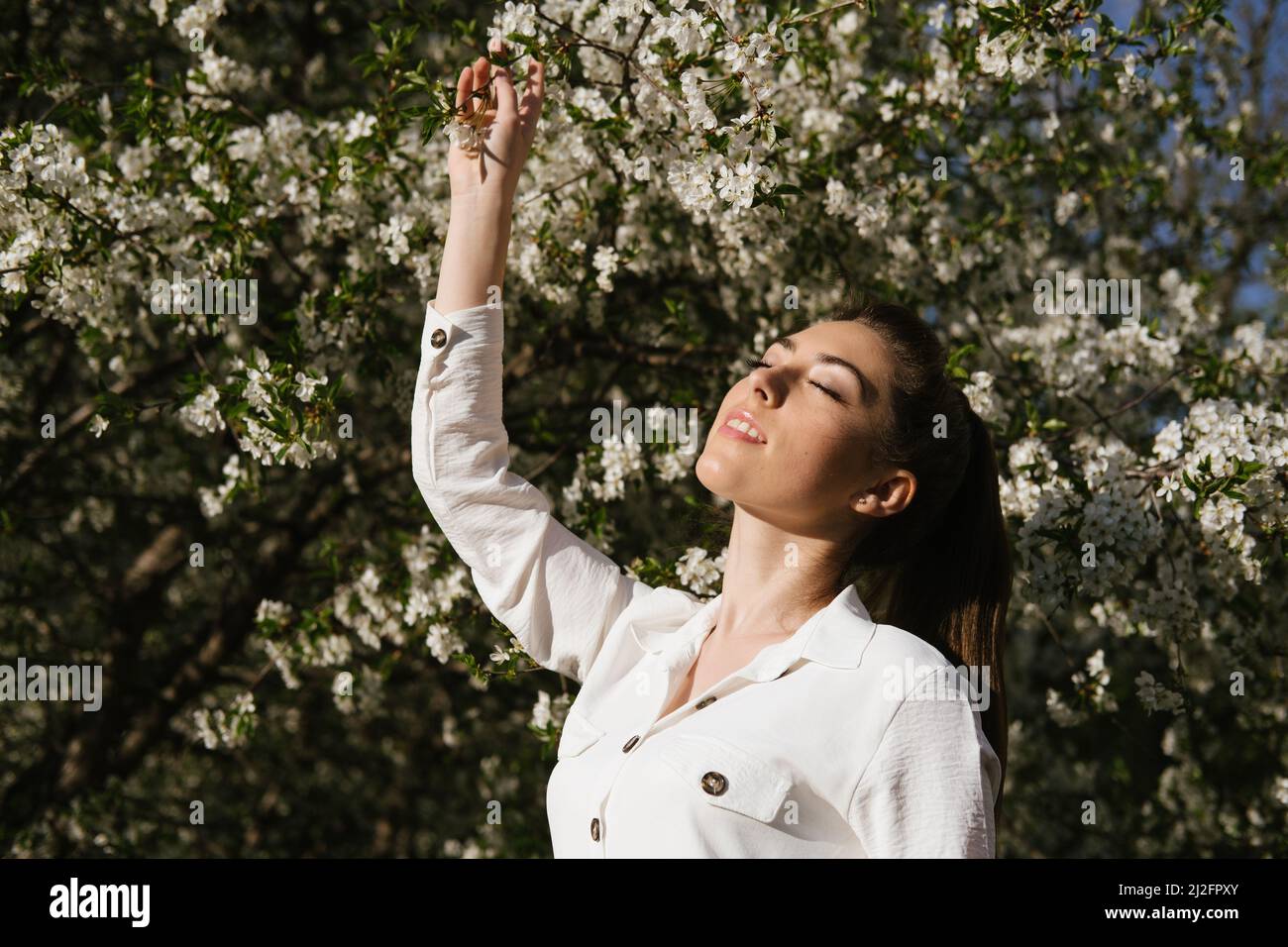 Outdoor portrait of happy ukrainian woman in cherry blossom garden ...