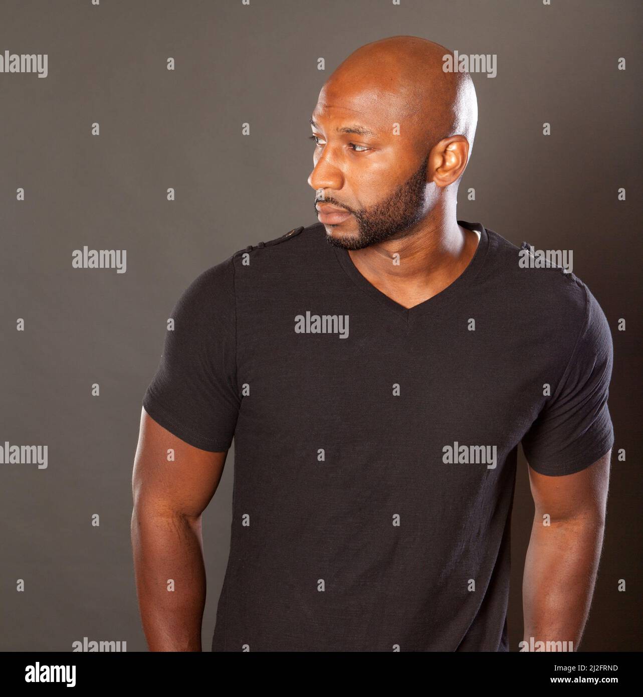 Young athletic man in a casual pose a dark t-shirt looking at the camera with a sesios attitude expression looking to the side Stock Photo Alamy