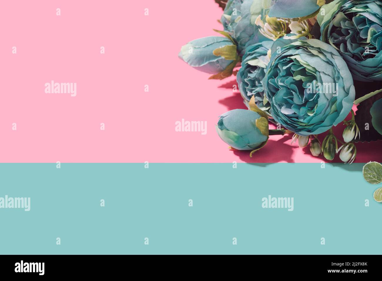 Artificial flowers bouquet on a blue and pink pastel background. Springtime minimal concept. Stock Photo