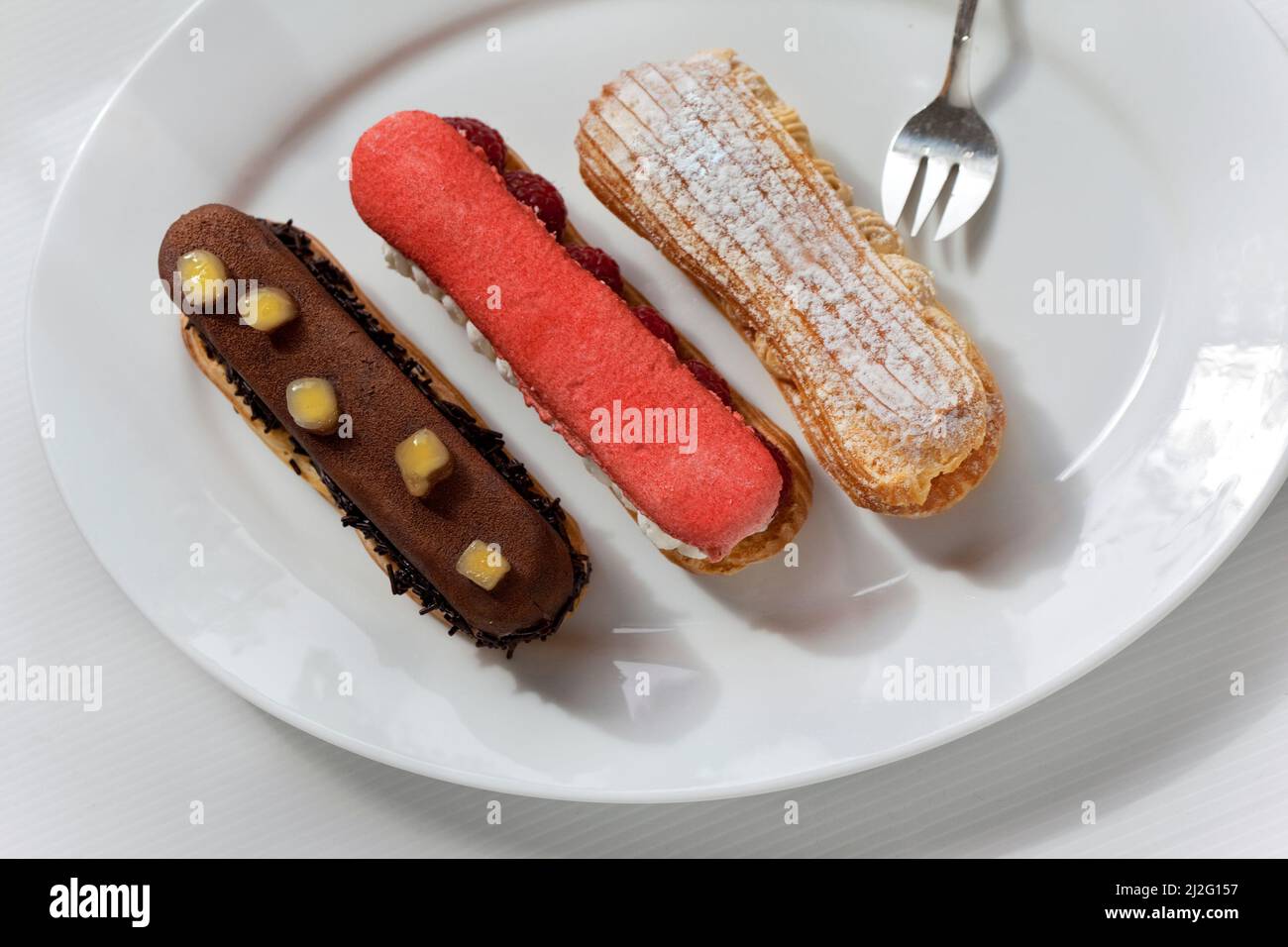 Three French Eclair cakes on a white plate Stock Photo