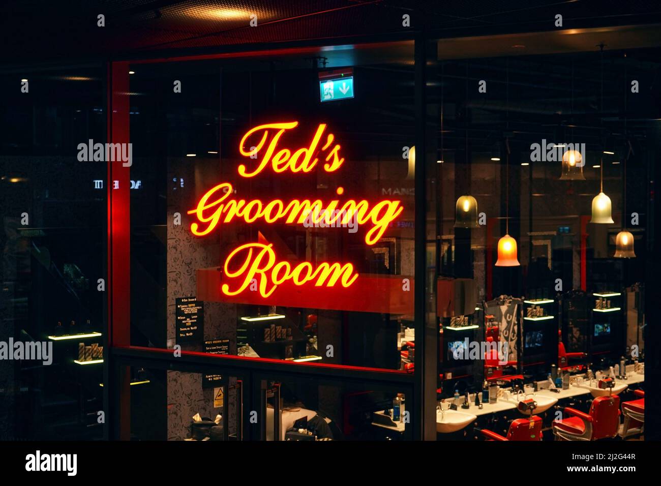 London, United Kingdom - February 01, 2019: Yellow neon script text logo on Ted's Grooming Room - subsidiary of Ted Baker - barber shop at one of thei Stock Photo