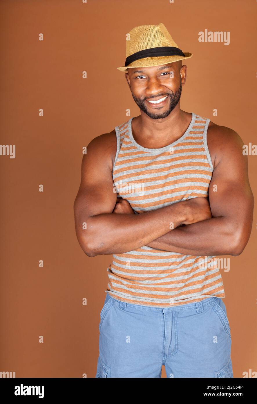Young fit African American man in a casual outfit against an earthtone ...