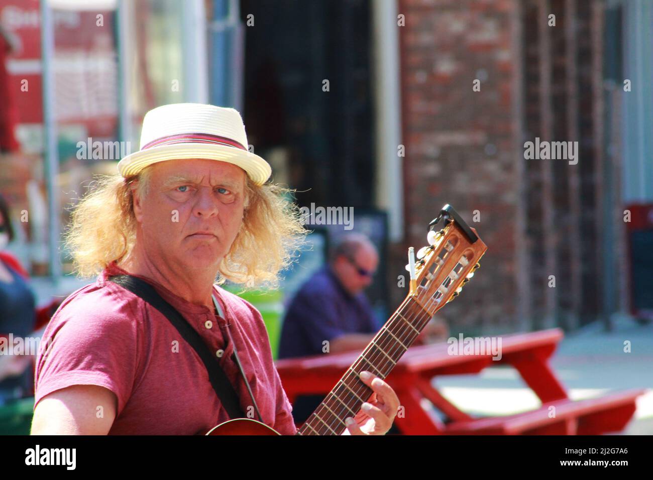 A busker playing a guitar on Water Street, St. John's, NL, Canada Stock Photo