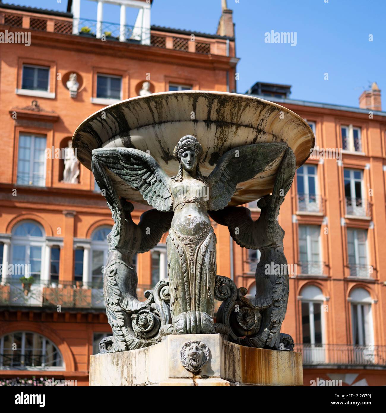 The beautiful Statue, Trinity fountain in the historical district of Toulouse, with red brick building in background, France. Stock Photo