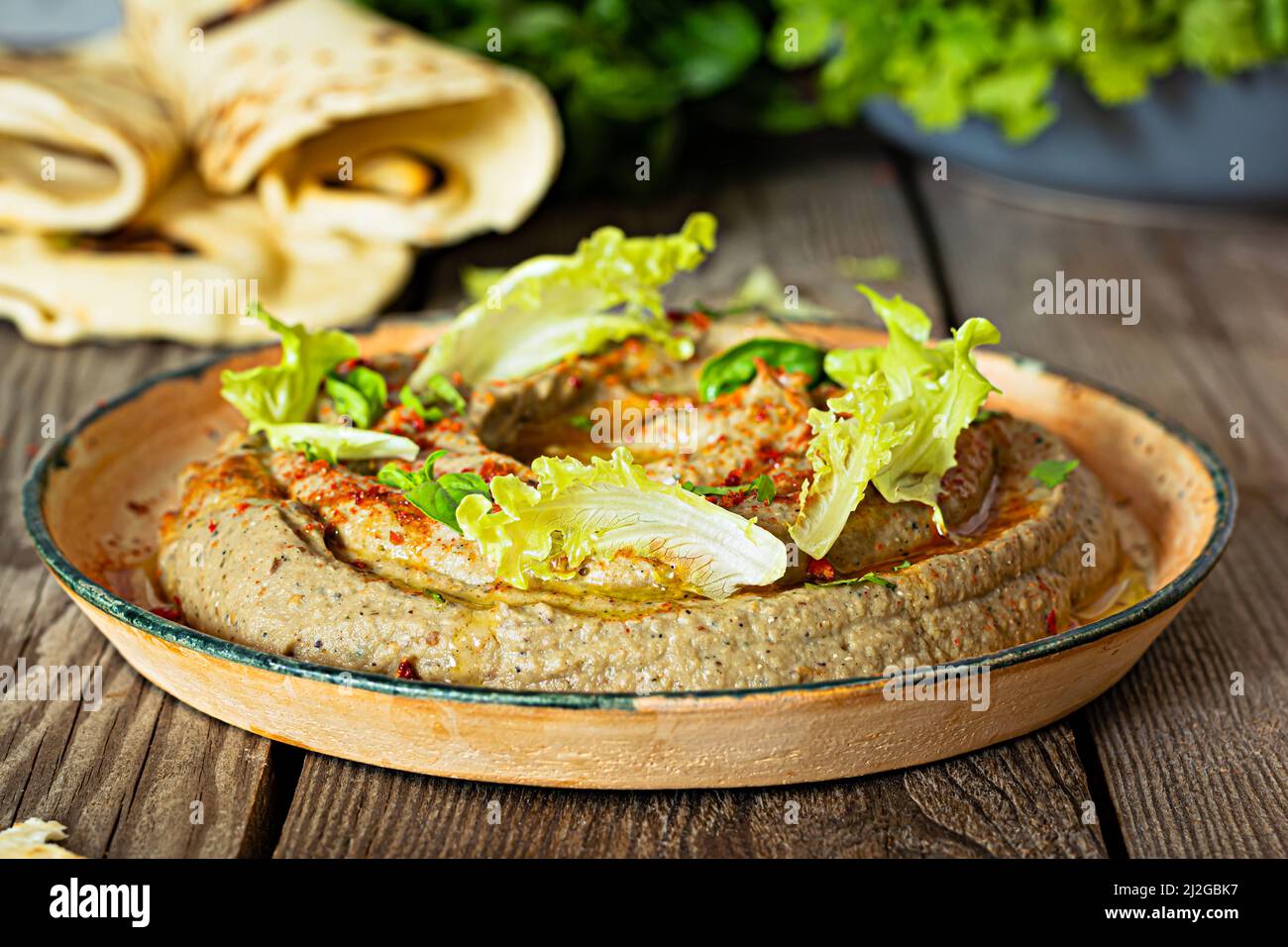 An oriental dish of baked eggplant babaganush (eggplant puree) with spices, herbs, lettuce and oriental flatbreads. Stock Photo